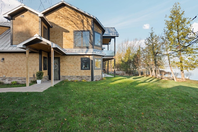 835 M-88, Bellaire, MI 49615 - view of side of property with a standing seam roof, a lawn, metal roof, and a balcony