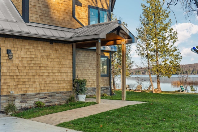 835 M-88, Bellaire, MI 49615 - view of property exterior with a standing seam roof, a water view, a lawn, and metal roof