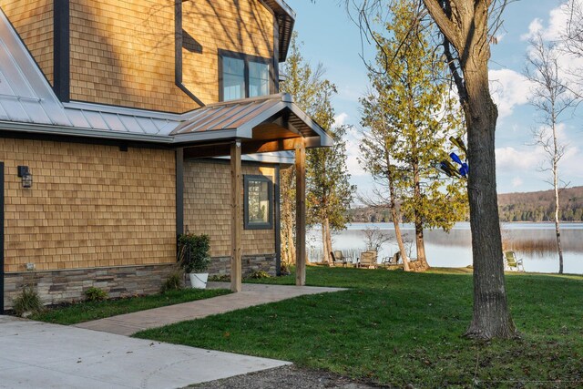 835 M-88, Bellaire, MI 49615 - view of home's exterior with a water view, a standing seam roof, a yard, and metal roof