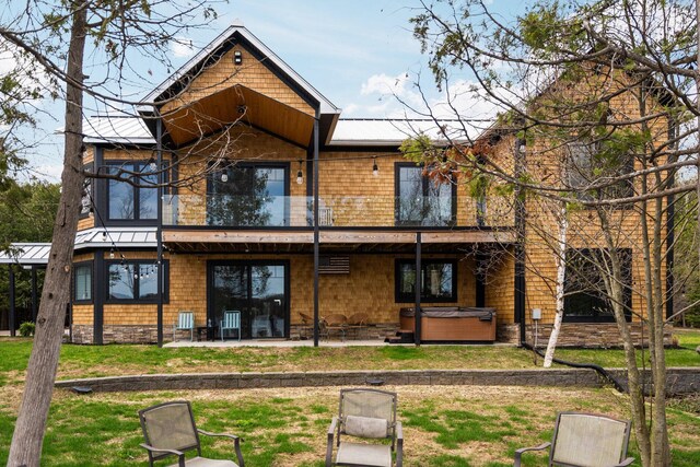 835 M-88, Bellaire, MI 49615 - rear view of house with a hot tub, a patio area, metal roof, a lawn, and a standing seam roof
