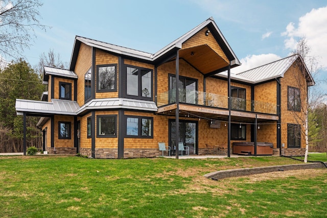 835 M-88, Bellaire, MI 49615 - rear view of house featuring a standing seam roof, a hot tub, metal roof, a balcony, and a patio