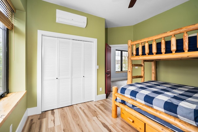 835 M-88, Bellaire, MI 49615 - bedroom with a wall mounted air conditioner, baseboards, a closet, wood finished floors, and a ceiling fan