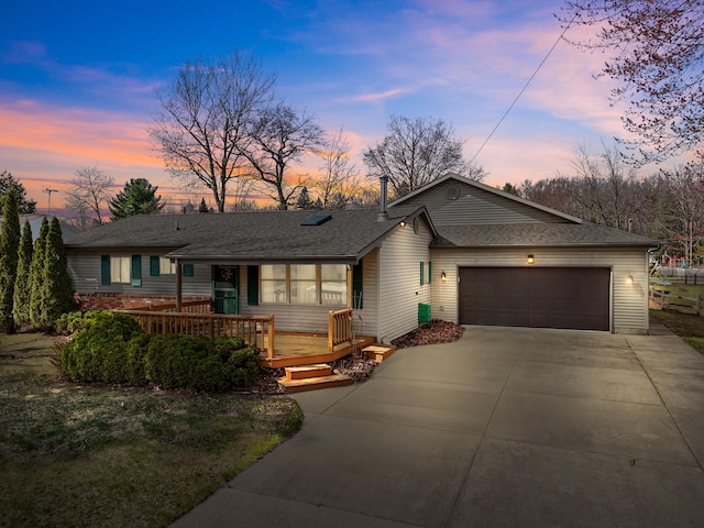 single story home with a wooden deck, driveway, a shingled roof, and a garage