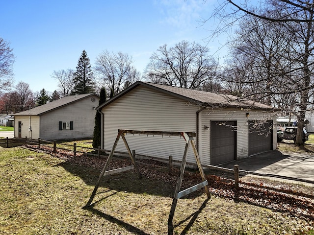 exterior space with a detached garage, fence, and an outbuilding