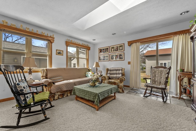 living room with a skylight, carpet floors, plenty of natural light, and baseboards