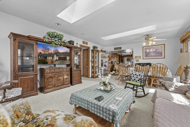 living area featuring a ceiling fan, a skylight, and light colored carpet