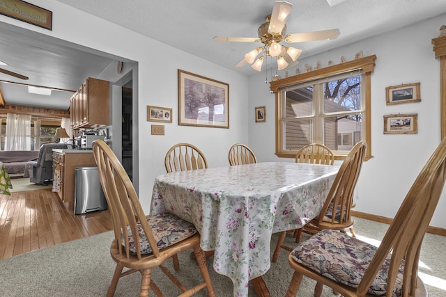 dining area featuring baseboards, ceiling fan, wood-type flooring, and a wealth of natural light