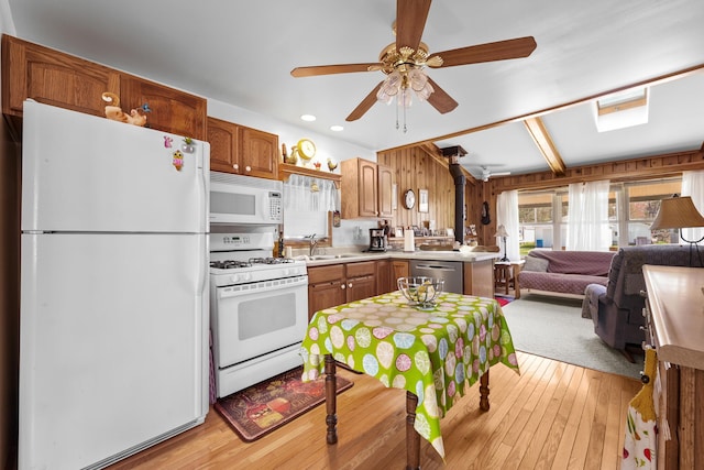 kitchen featuring ceiling fan, a sink, light countertops, open floor plan, and white appliances