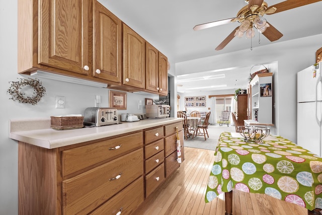 kitchen with light wood-style floors, light countertops, ceiling fan, and brown cabinets