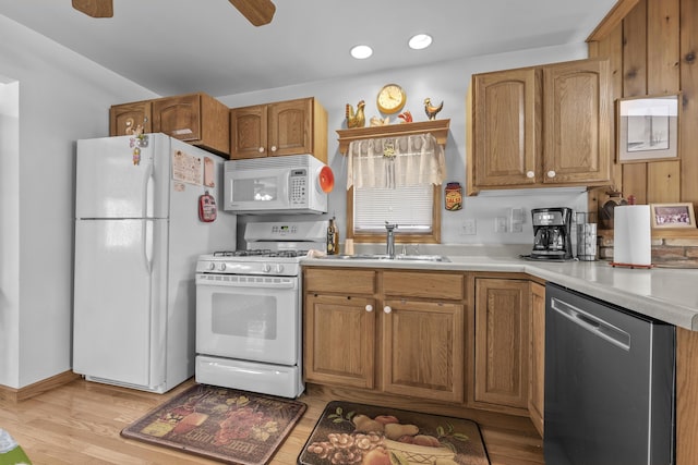 kitchen featuring a sink, light countertops, brown cabinetry, and white appliances