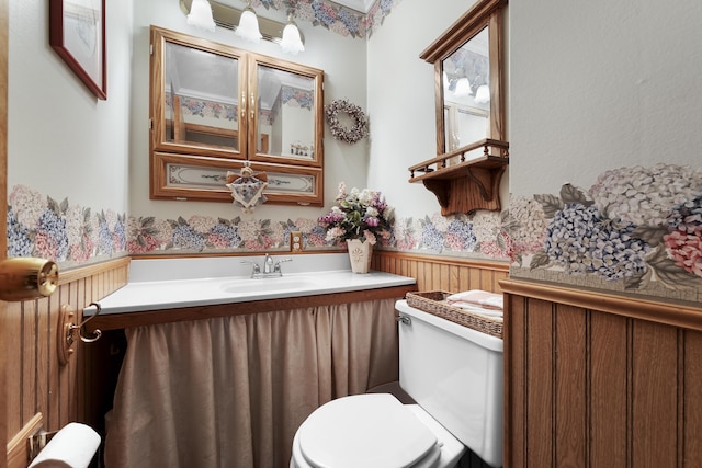bathroom with vanity, wood walls, wainscoting, and toilet