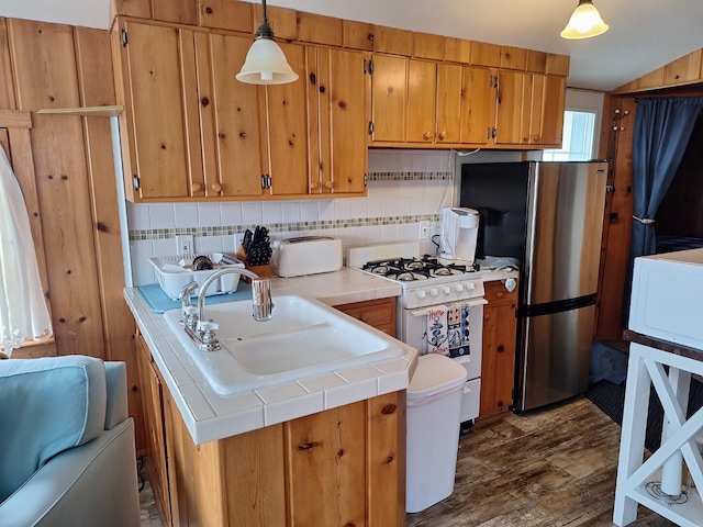 kitchen with white gas range, tile countertops, dark wood finished floors, a sink, and freestanding refrigerator