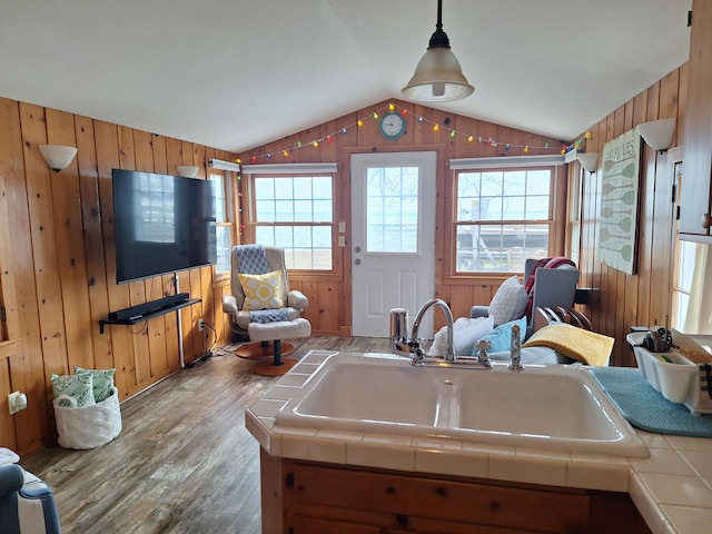 kitchen featuring tile countertops, wood walls, wood finished floors, and lofted ceiling