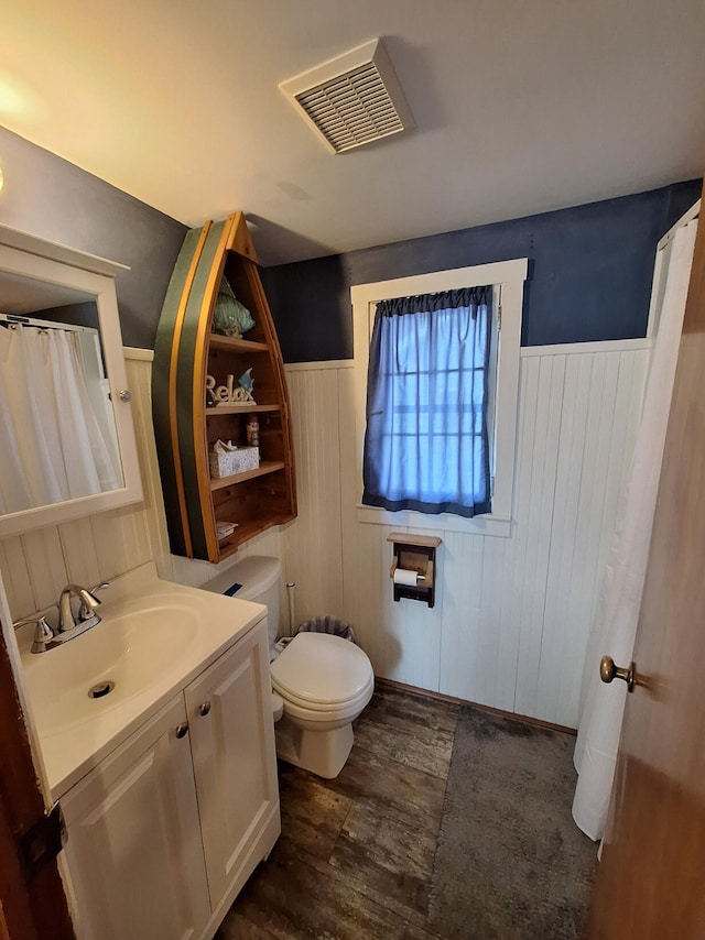 full bathroom featuring a wainscoted wall, toilet, wood finished floors, and visible vents