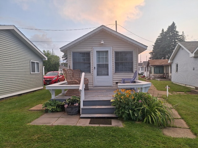 back of house at dusk featuring a wooden deck and a yard