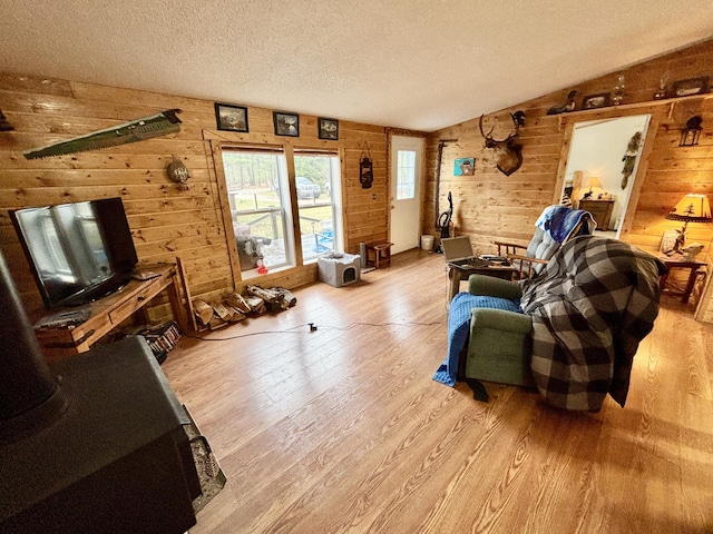 3313 Pleasant View Dr, Lewiston, MI 49756 - living area featuring wood walls, light wood finished floors, vaulted ceiling, and a textured ceiling