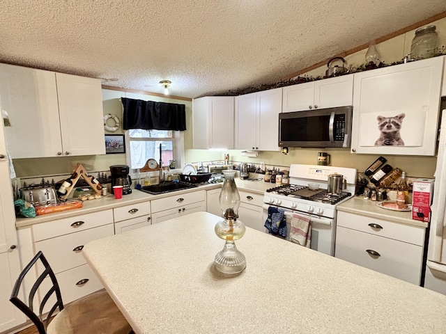 3313 Pleasant View Dr, Lewiston, MI 49756 - kitchen featuring stainless steel microwave, gas range gas stove, a textured ceiling, light countertops, and white cabinets
