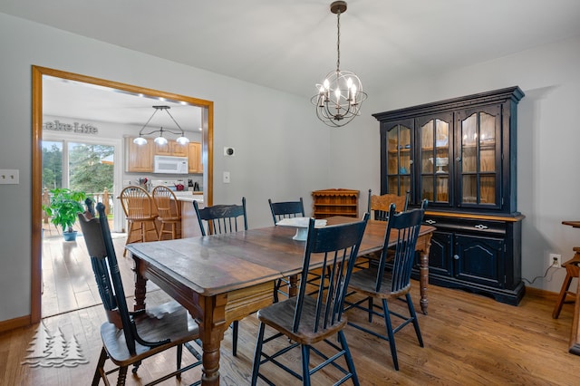 3897 S Mielke Way Rd, Lewiston, MI 49756 - dining area featuring an inviting chandelier, light wood finished floors, and baseboards
