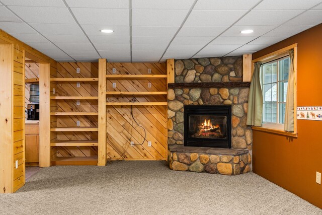 1350 Pine Point Dr, Lewiston, MI 49756 - unfurnished living room featuring carpet floors, a stone fireplace, recessed lighting, a drop ceiling, and wooden walls
