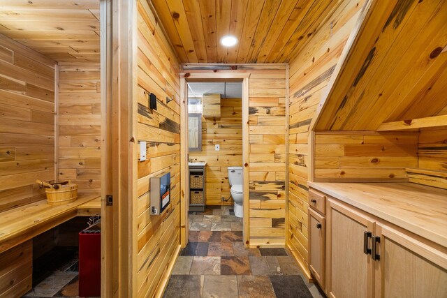 1350 Pine Point Dr, Lewiston, MI 49756 - hallway with wood walls, wooden ceiling, dark stone finish floors, and recessed lighting