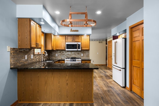 1350 Pine Point Dr, Lewiston, MI 49756 - kitchen featuring premium appliances, a sink, a peninsula, brown cabinets, and tasteful backsplash