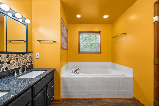 1350 Pine Point Dr, Lewiston, MI 49756 - bathroom featuring wood finished floors, double vanity, a bath, and backsplash