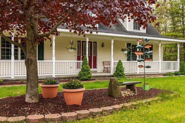1350 Pine Point Dr, Lewiston, MI 49756 - farmhouse inspired home featuring a porch, a front lawn, and a shingled roof
