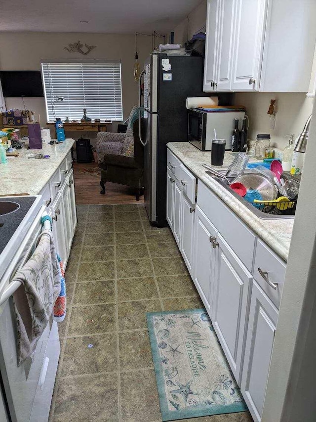 11052 W Higgins Lake Dr, Roscommon, MI 48653 - kitchen with light countertops, white cabinetry, freestanding refrigerator, and electric stove