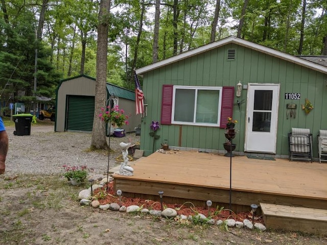 11052 W Higgins Lake Dr, Roscommon, MI 48653 - view of front of property featuring a garage, an outbuilding, gravel driveway, and a deck