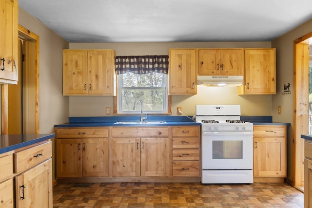 4441 Judy Ave, Lewiston, MI 49756 - kitchen featuring white gas stove, under cabinet range hood, a sink, light brown cabinetry, and dark countertops