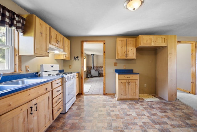 4441 Judy Ave, Lewiston, MI 49756 - kitchen featuring white gas stove, under cabinet range hood, light brown cabinetry, a wood stove, and a sink