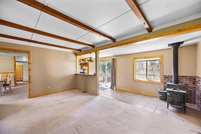 4441 Judy Ave, Lewiston, MI 49756 - unfurnished living room featuring a wood stove, baseboards, beamed ceiling, tile patterned floors, and carpet