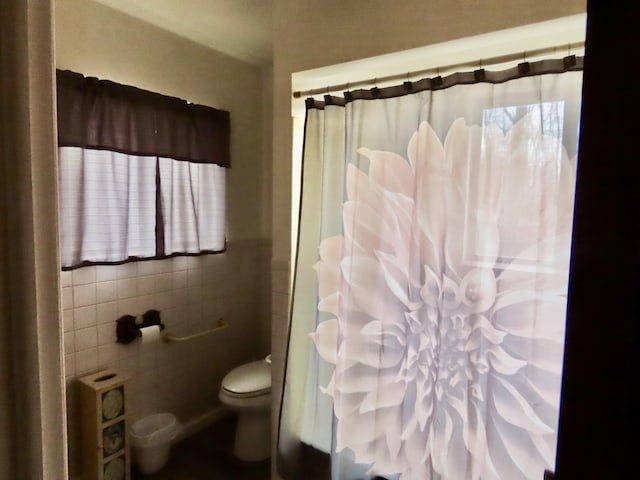 bathroom with tile walls, toilet, and curtained shower