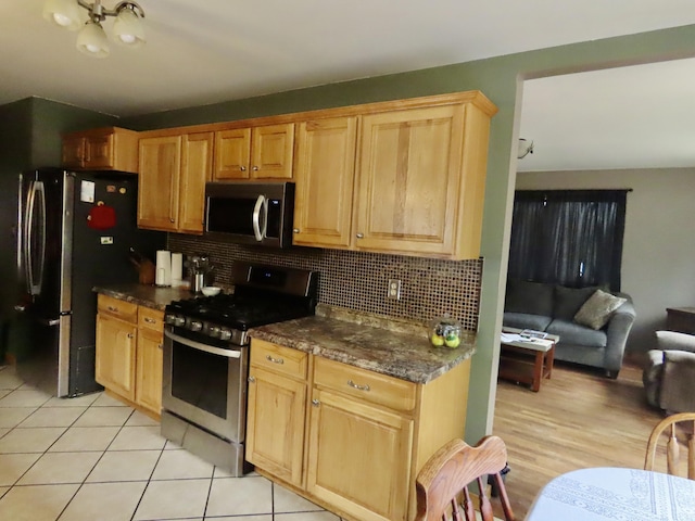 kitchen with light tile patterned floors, decorative backsplash, stainless steel appliances, and open floor plan