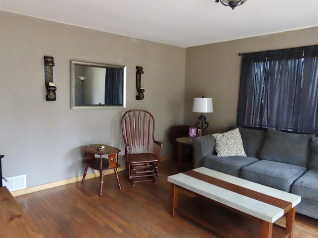 living area featuring baseboards, visible vents, and wood finished floors