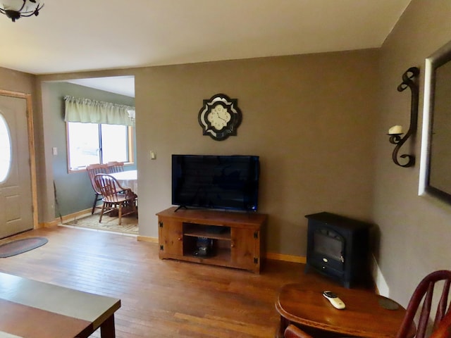 living room featuring baseboards, a wood stove, and wood finished floors