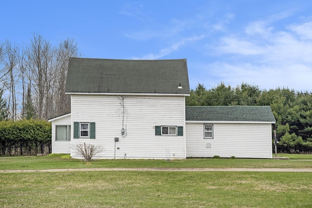view of side of property featuring a lawn and roof with shingles