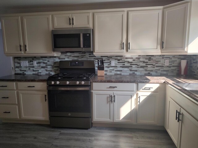 10232 E Airport Rd, Saint Helen, MI 48656 - kitchen featuring stainless steel appliances, decorative backsplash, wood finished floors, and white cabinetry