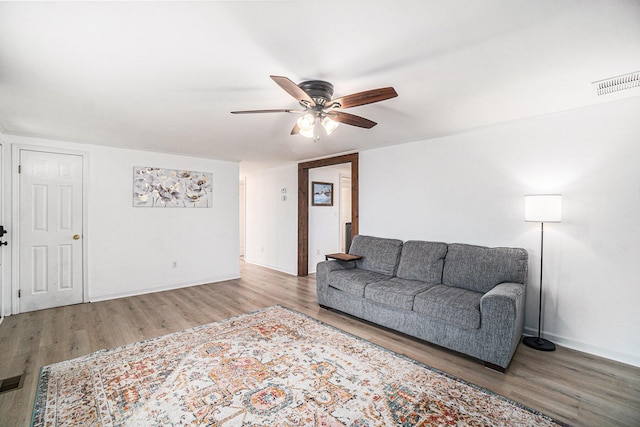 living area featuring baseboards, ceiling fan, wood finished floors, and visible vents