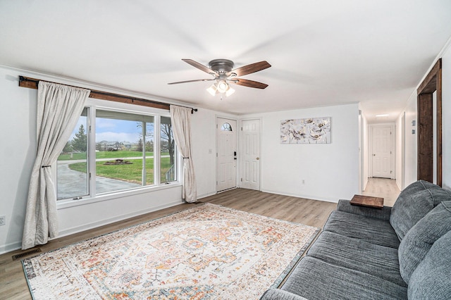 living area with light wood-style floors, baseboards, ceiling fan, and visible vents
