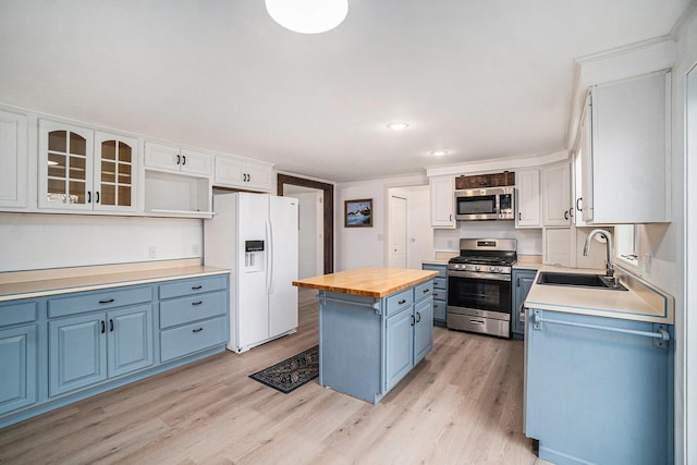 kitchen featuring butcher block countertops, blue cabinets, a sink, stainless steel appliances, and light wood-style flooring