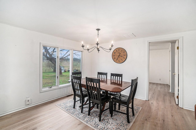 dining space featuring baseboards, light wood-style flooring, and a chandelier
