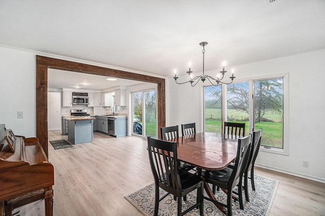 dining area featuring an inviting chandelier, light wood-style flooring, baseboards, and a wealth of natural light