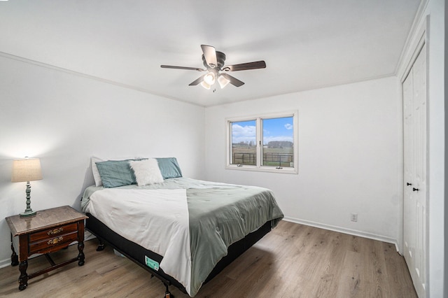 bedroom featuring light wood-type flooring, a ceiling fan, baseboards, and a closet