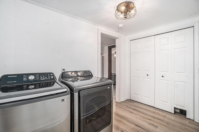 laundry room with crown molding, laundry area, washing machine and dryer, and light wood-style floors