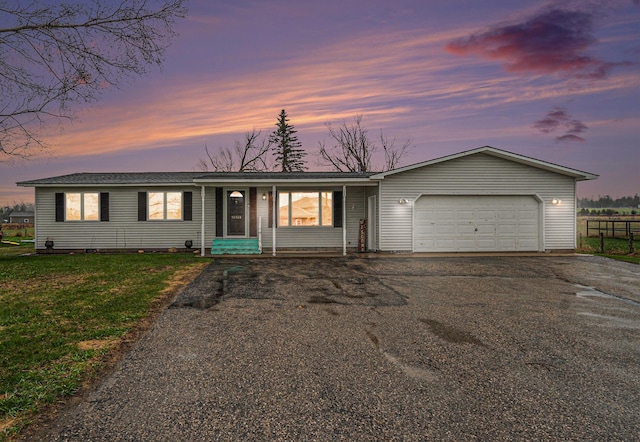 ranch-style home with a lawn, a garage, fence, and driveway