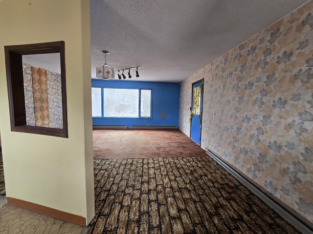 carpeted empty room featuring baseboards, a notable chandelier, wallpapered walls, and a textured ceiling