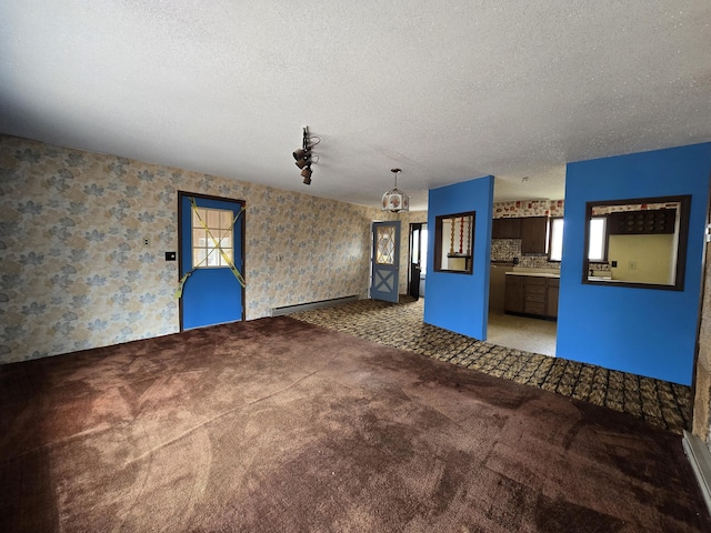 unfurnished living room with wallpapered walls, a textured ceiling, and light carpet