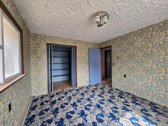 spare room with wallpapered walls and a textured ceiling