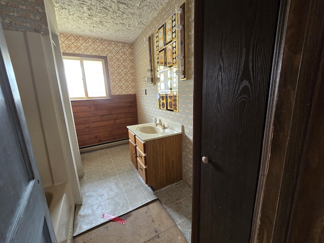 full bath featuring tile patterned floors, vanity, wallpapered walls, and a textured ceiling